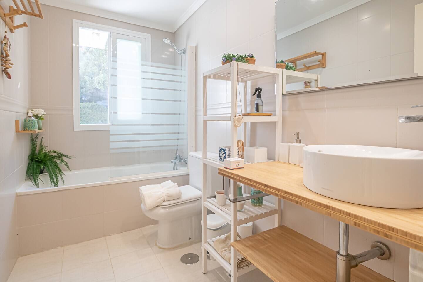 Un bagno moderno con vasca, servizi igienici e un mobile bagno in legno con lavandino.