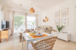 A modern living room with a dining table, sofa, and a television. - Calm and bright 1bedroom with Terrace & pool views (Mijas)