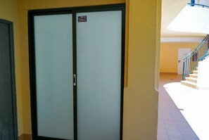 A double door with a sign, a staircase with blue railings, and a tiled floor. - Bright & quiet 2 bedroom with large terrace & pool (Mijas)