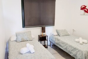 A hotel room with two beds, a TV, a bedside table, and a wall-mounted artwork. - Bright & quiet 2 bedroom with large terrace & pool (Mijas)