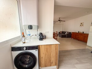 Eine kleine Küche mit einer Waschmaschine, einer Kaffeemaschine und einer Wasserflasche auf der Arbeitsfläche.
