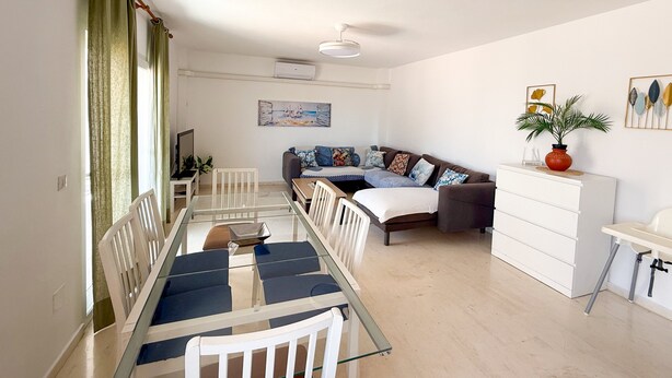 Uma sala de estar moderna com uma mesa de jantar de vidro, um sofá, uma cama e uma cômoda branca.