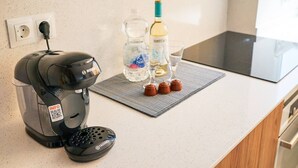 Cozinha com cafeteira, uma garrafa de água e um copo de vinho sobre o balcão.