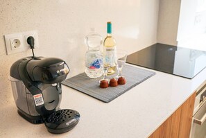 Eine Küche mit einer Kaffeemaschine, einer Wasserflasche und einem Weinglas auf der Arbeitsfläche.