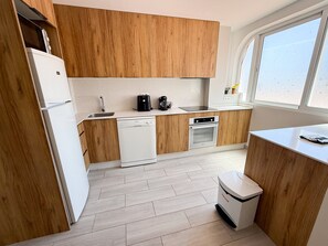 Eine moderne Küche mit Holzausstattung, einem Geschirrspüler, einem Backofen und einem Fenster für natürliches Licht.