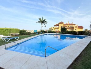 Ein rechteckiger Pool mit einer Metallleiter, umgeben von einer Betonplattform.
