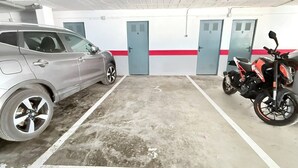 En parkeringskælder med bil og motorcykel, beton gulv og døre nummereret 1 til 5.