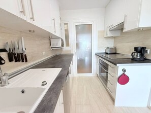 Eine moderne Küche mit einem weißen Spülbecken, einer dunklen Arbeitsplatte und Edelstahlgeräten.