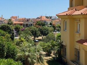 A residential area with terracotta-roofed houses, lush greenery, and a clear sky. - Two bedroom Garden Apt with Sea Views & Pool (Mijas)