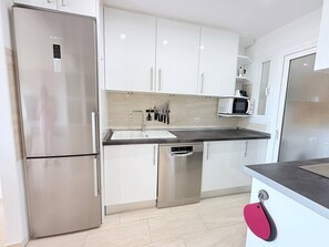 A modern kitchen with stainless steel appliances, white cabinetry, and a built-in microwave. - Two bedroom Garden Apt with Sea Views & Pool (Mijas)