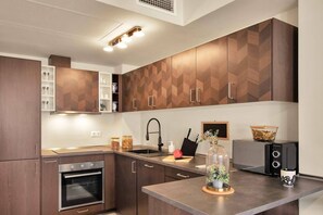 Eine moderne Küche mit Holzschränken, integriertem Backofen, Spüle und Mikrowelle.