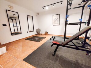Une salle de sport équipée de matériel d’exercice, d’un banc et d’un miroir fixé au mur.