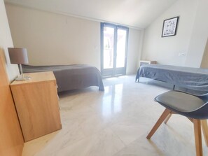 Une chambre avec deux lits, un bureau, une chaise et une fenêtre.