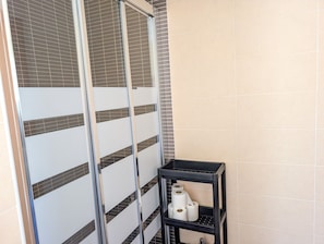 Ein Badezimmer mit Duschbereich, Toilette und Ablage für Toilettenartikel.