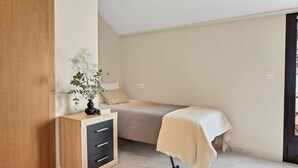 A bedroom with a bed, bedside table, and a small desk with drawers.