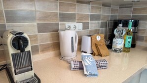 Eine Küchenarbeitsplatte mit Kaffeemaschine, Toaster, einer Wasserflasche, Olivenöl und einer Papiertüte.