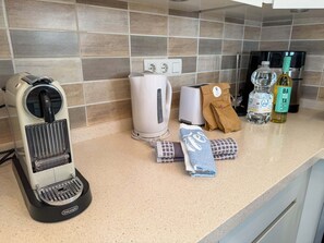 Eine Küchenarbeitsplatte mit Kaffeemaschine, Toaster, einer Wasserflasche, Olivenöl und einer Papiertüte.