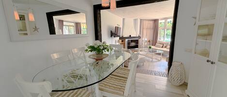 Un espace repas moderne avec une table en verre, des chaises blanches et un arrangement floral central.