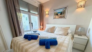 Ein Hotelzimmer mit Bett, Nachttisch, Lampe und einem Fenster mit Vorhängen.