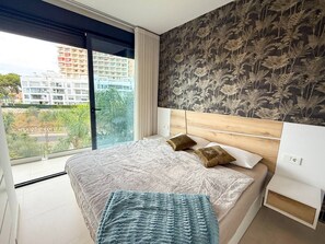 Ein Schlafzimmer mit einem großen Bett, Blick auf Gebäude und einer Wand mit Muster.