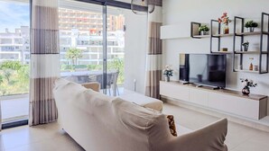 Un salon moderne avec un canapé, un téléviseur et des étagères ornées de plantes.