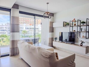 A modern living room with a sofa, TV, and shelves with plants. - Torremar Luxe: upscale 2bed apartment by the beach (Torremolinos)