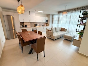 A modern kitchen with white cabinets, a stainless steel refrigerator, and a dining table with chairs. - Torremar Luxe: upscale 2bed apartment by the beach (Torremolinos)