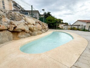 Ein Swimmingpool mit Steinmauer und gepflastertem Deck.
