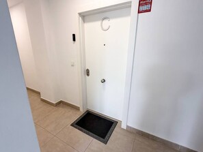 Eine weiße Tür mit einem runden Griff und einer Fußmatte davor.
