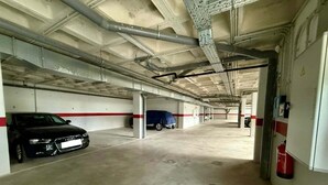 Un parking avec des planchers en béton, des poutres métalliques et un extincteur fixé au mur.