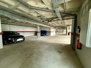 A parking garage with concrete floors, metal beams, and a fire extinguisher on the wall. - Torremar Luxe: upscale 2bed apartment by the beach (Torremolinos)