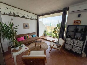 Ein Wohnzimmer mit einer Couch, Sesseln, einem Couchtisch und einer Vitrine mit Kunstwerken.