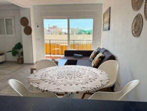 Ein Essbereich mit rundem Tisch und Stühlen, einer Couch und Blick ins Freie.