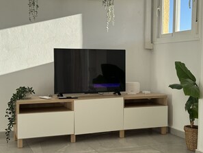 Ein modernes Wohnzimmer mit Flachbildfernseher, Holzunterhaltungseinheit und Topfpflanzen.