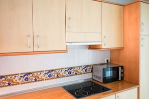A kitchen with wooden cabinets, a microwave, and a stove. - Relaxing 2 Bed duplex: seaviews, terrace & rooftop (Marbella)