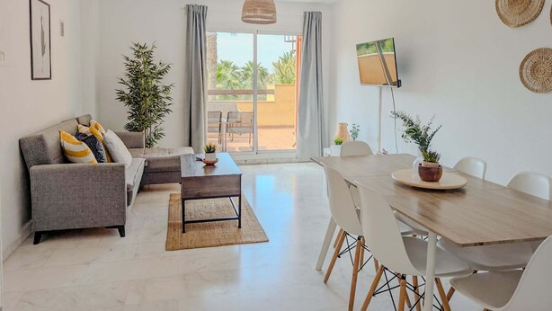 Una sala moderna con sofá, mesa de comedor, sillas y un amplio ventanal con vistas.