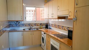 Una cocina con armarios de madera, lavadora, microondas y un lavamanos.