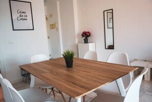 A modern dining area with a wooden table, white chairs, a potted plant, and framed artwork on the walls. - Relaxing 2 Bed duplex: seaviews, terrace & rooftop (Marbella)