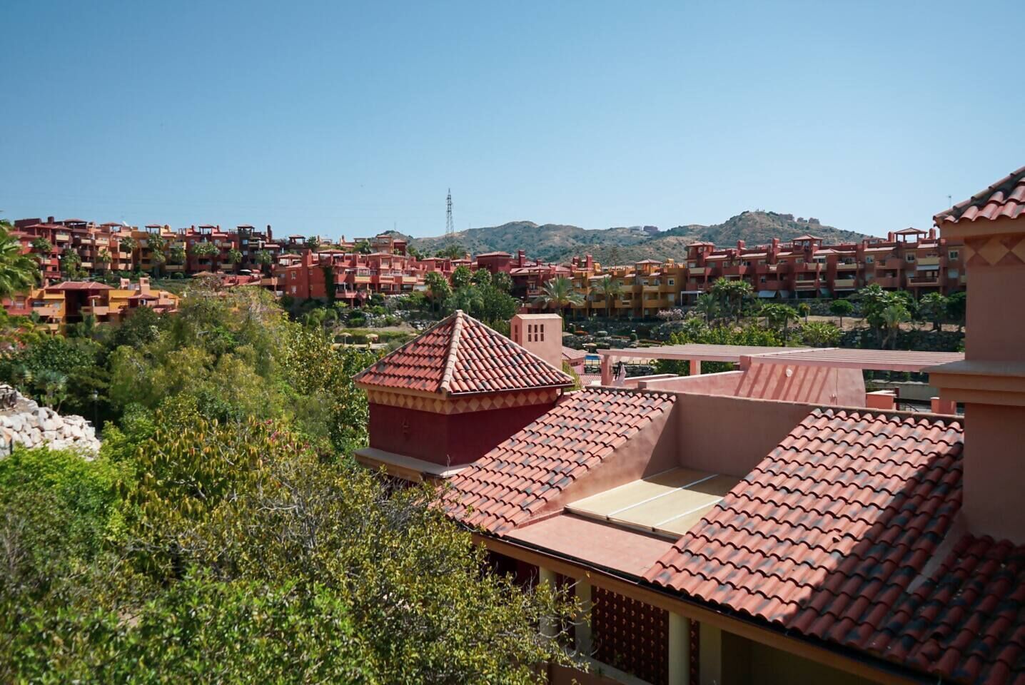 Un quartier résidentiel composé de plusieurs immeubles, dont certains sont coiffés de toits en tuiles rouges, et qui offre une vue dégagée sur le paysage environnant.