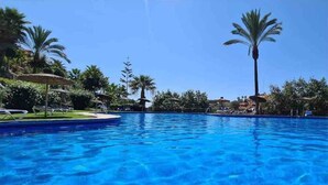 Una piscina azul clara rodeada de palmeras y sillas de descanso.