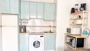 Une cuisine compacte équipée d’un lave-linge, d’un four à micro-ondes et d’un grille-pain.