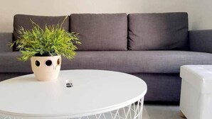 Une table ronde blanche ornée d’un motif géométrique, une plante en pot et une télécommande.