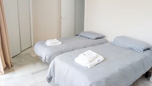 Ein Hotelzimmer mit zwei Betten, einem Kleiderschrank und einer Badezimmertür.