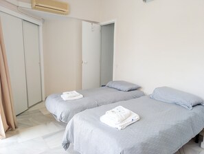 Ein Hotelzimmer mit zwei Betten, einem Kleiderschrank und einer Badezimmertür.