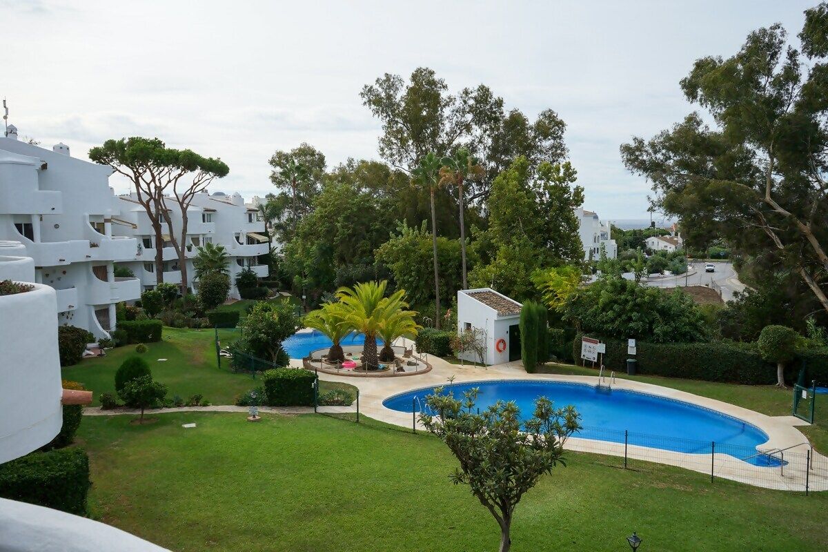A residential area with a swimming pool, white buildings, and green lawns.