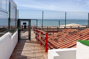 En træterrasse med hegn i metal, med udsigt over havet.