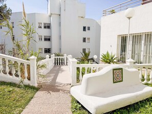 A pathway leading to a white building with multiple windows and balconies. - Casa La Luna: ¡Cozy and sunny 1BR on the beach! (Mijas)