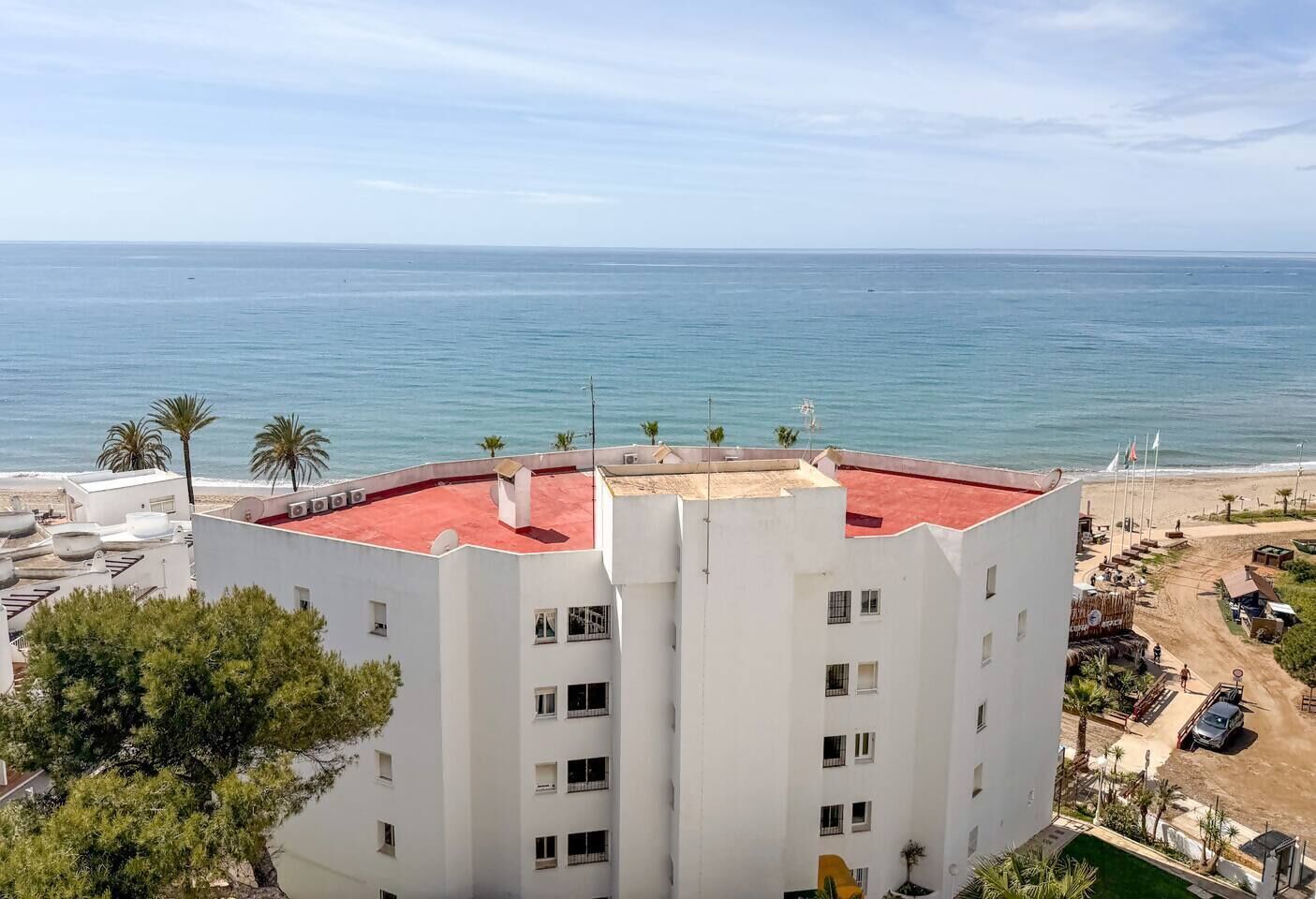 Un immeuble de grande hauteur, avec un toit rouge, qui offre une vue sur une plage et la mer.
