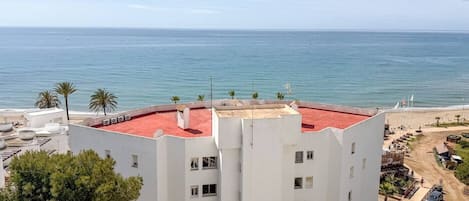 Un immeuble de grande hauteur, avec un toit rouge, qui offre une vue sur une plage et la mer.