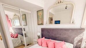 Une chambre à coucher avec un lit, un miroir, une armoire et une table de chevet.